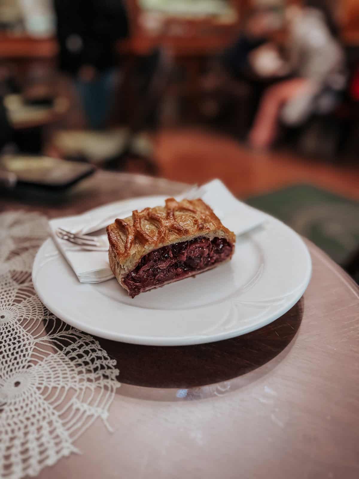 a cherry strudel with golden brown crust that looks crispy on a simple white plate