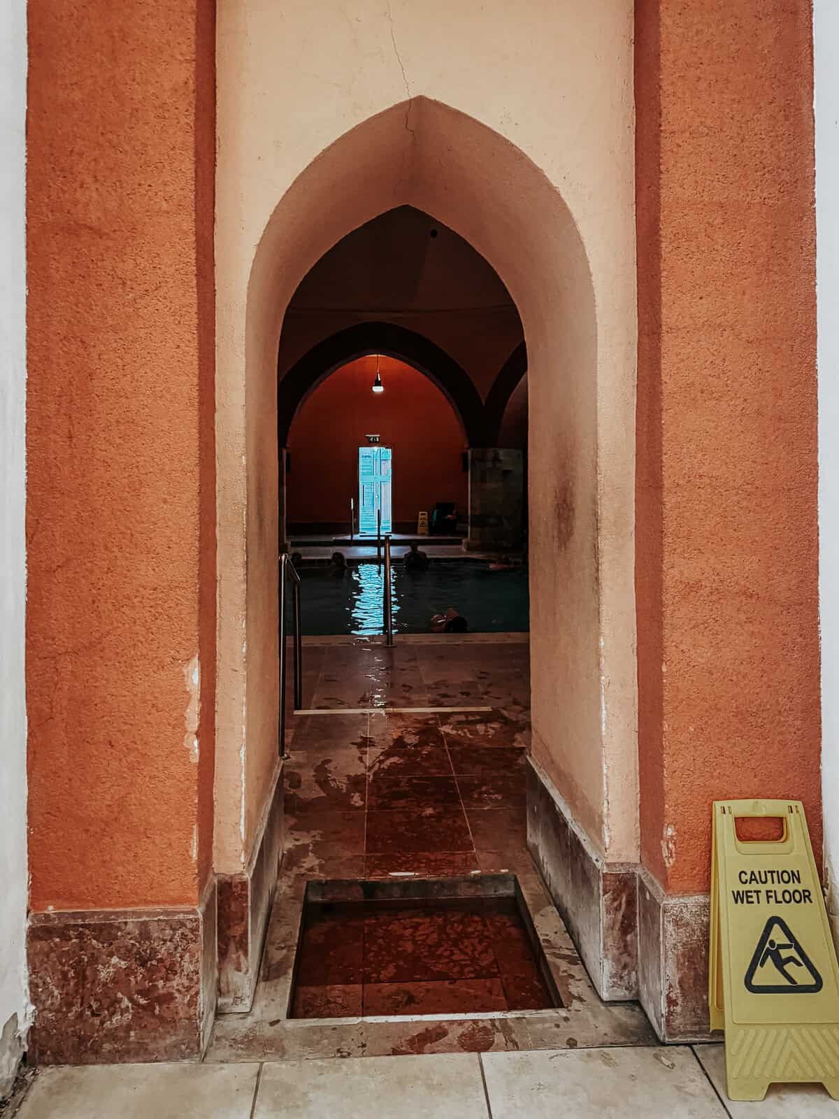 A view through an arched doorway into a swimming pool area, with a 