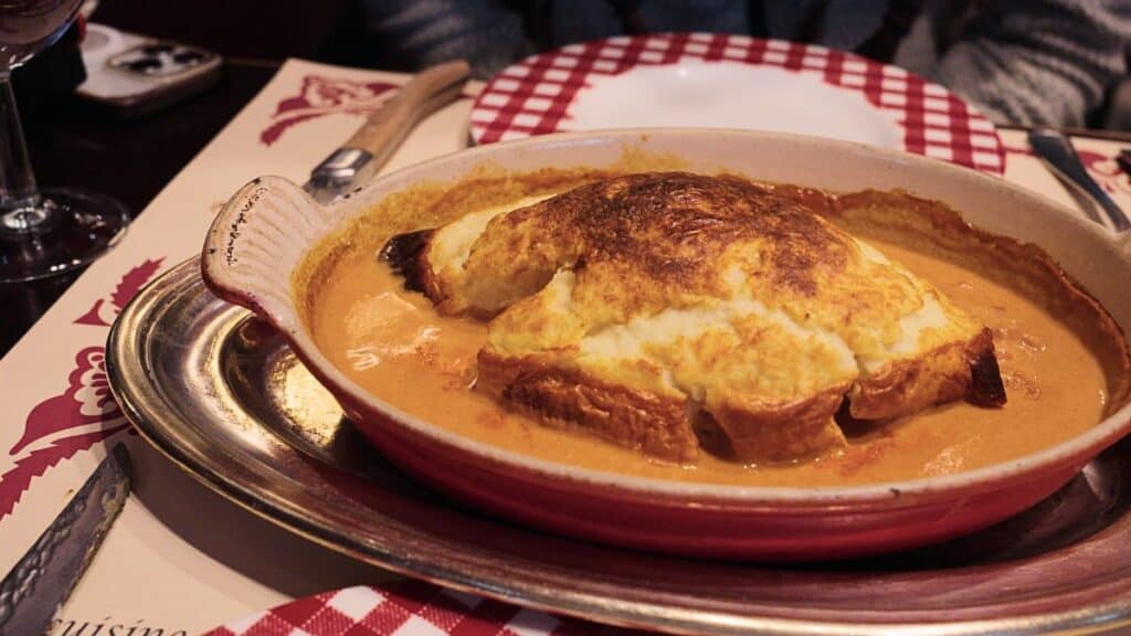 a quenelle de brochet in a bowl of orange sauce