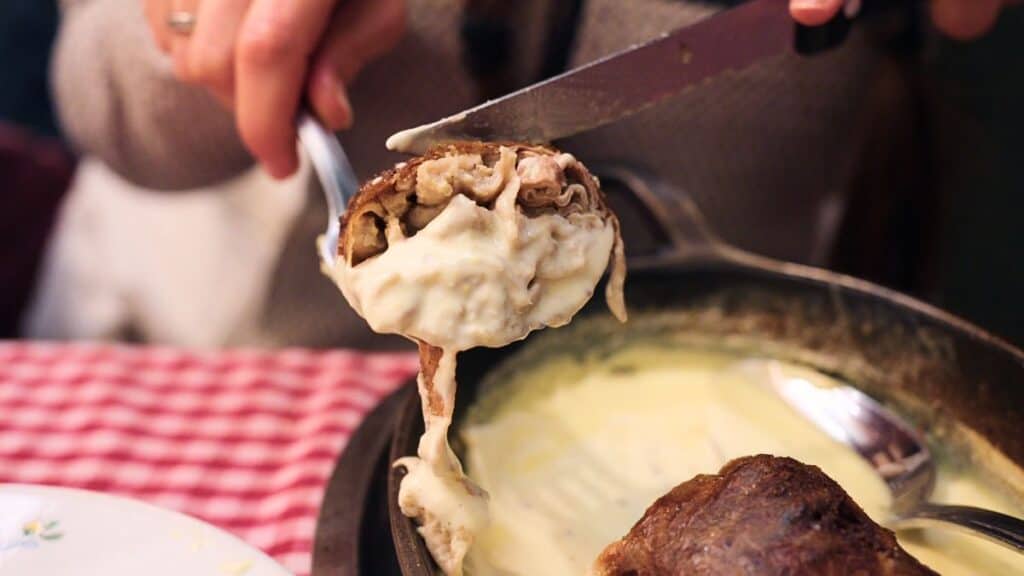 Andouillette sausage sliced open and covered in creamy sauce at a Lyon bouchon