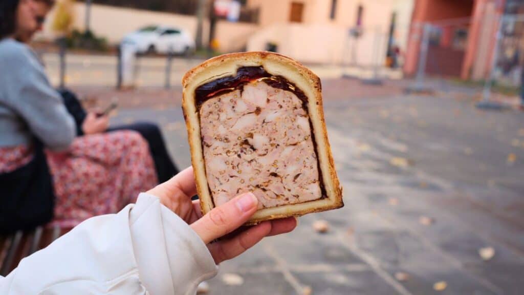 Slice of pâté en croûte showing layers of seasoned meat baked inside pastry