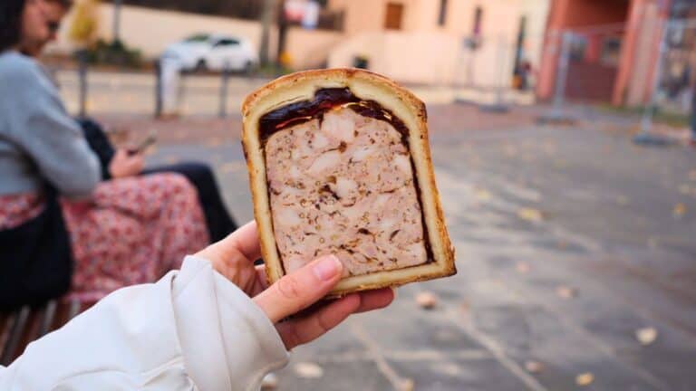 Slice of pâté en croûte showing layers of seasoned meat baked inside pastry