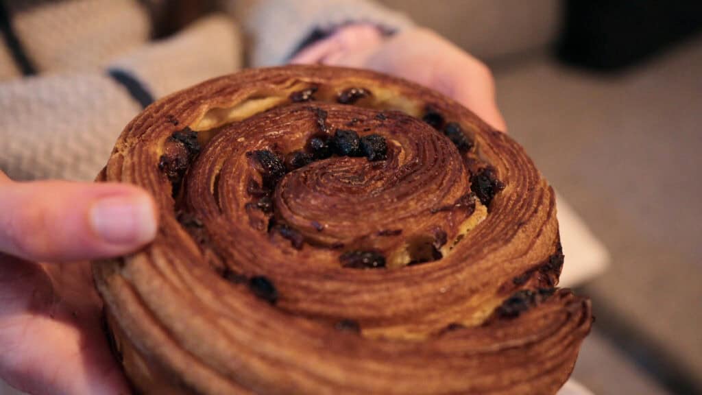 Raisin roll pastry from a Lyon bakery, showing crisp laminated layers and caramelized raisins