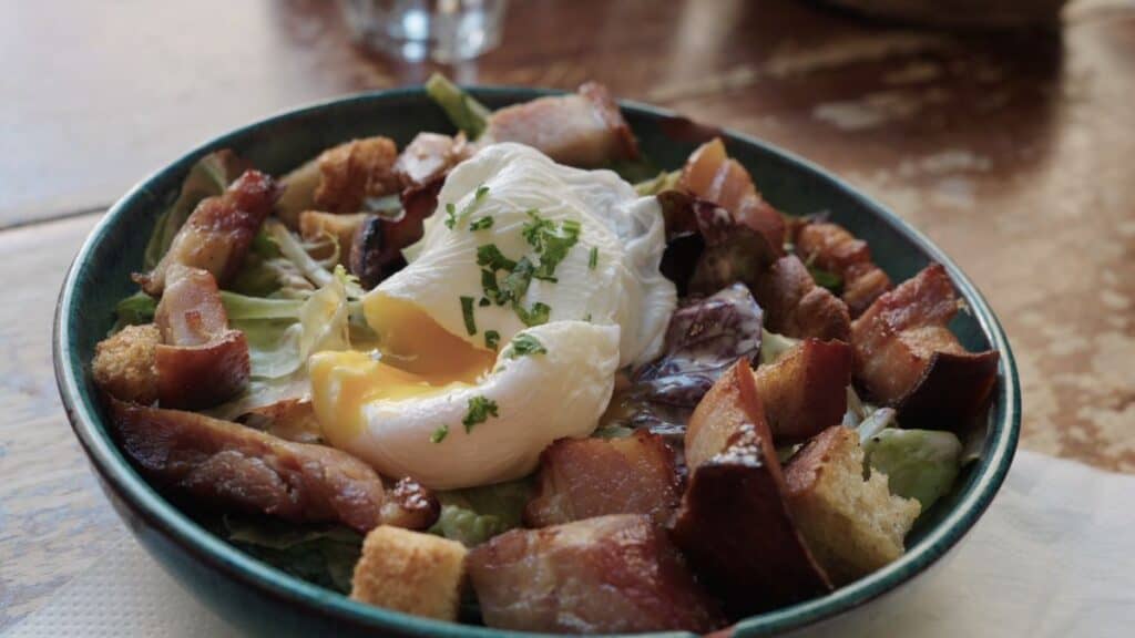 Classic salade Lyonnaise with frisée lettuce, thick bacon, croutons, and a runny poached egg