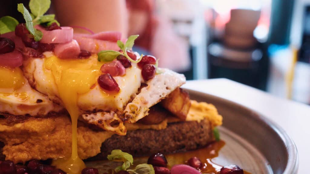 Harissa hummus toast with fried eggs and pomegranate at a trendy brunch spot in Glasgow