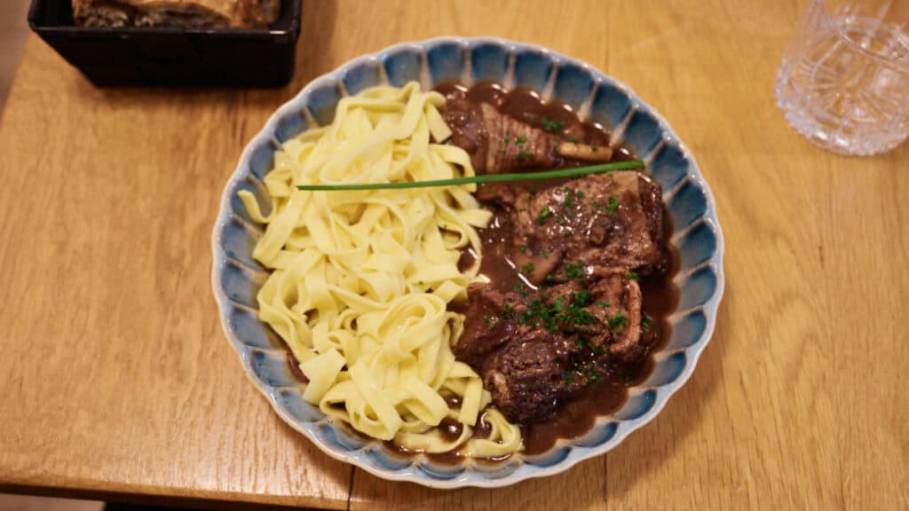 French beef stew with ribbon pasta served in Burgundy-style red wine sauce on a wooden table