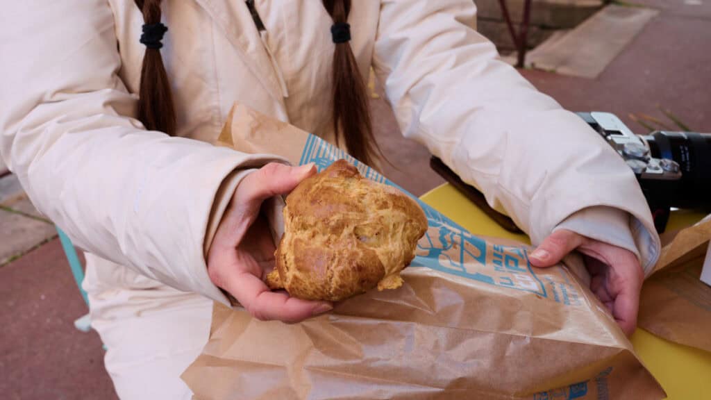 Fresh French choux pastry held in hand at a local bakery stop during a road trip