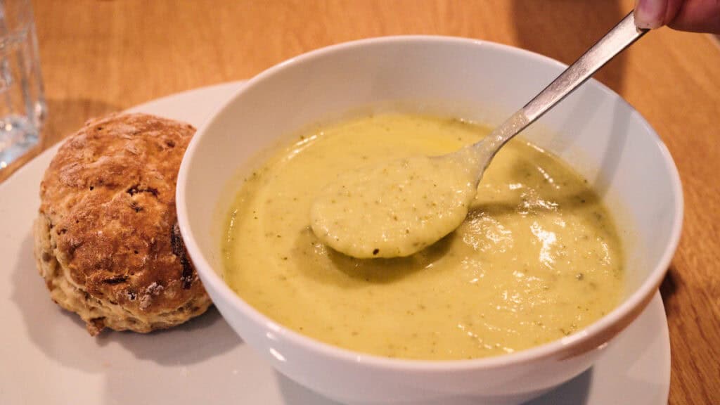Bowl of zucchini soup with a savory scone at a community café in Glasgow